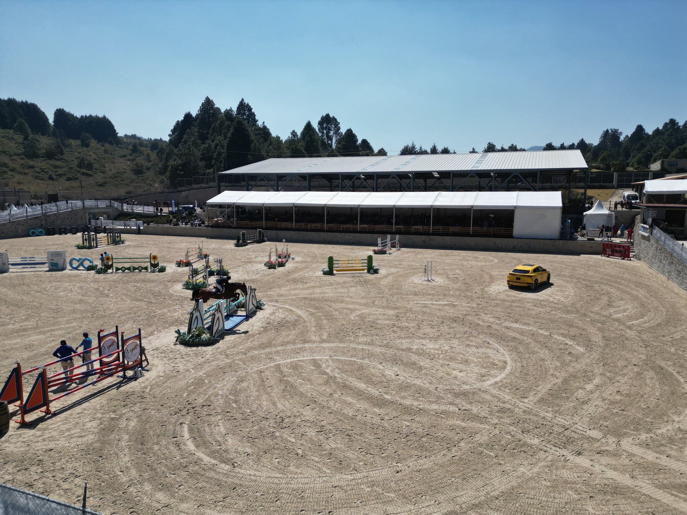 Vista aérea de la pista principal con un recorrido montado; detrás, la pista techada y el bosque de pinos.