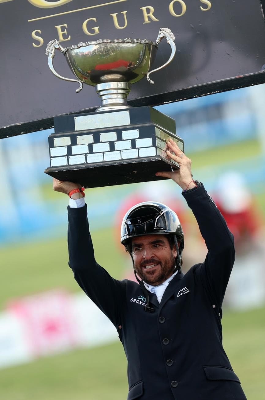 Nicolás Pizarro sonríe y levanta un trofeo con ambas manos.